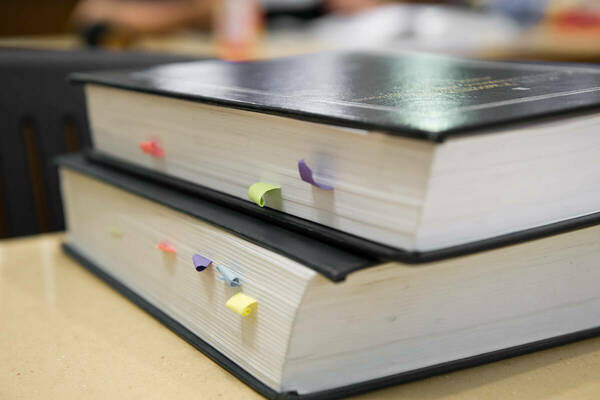 Two large books with dark covers and colorful tabs stacked on one another on top of desk